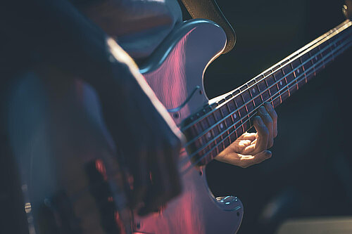 A base guitar, the hands playing the guitar are visible.